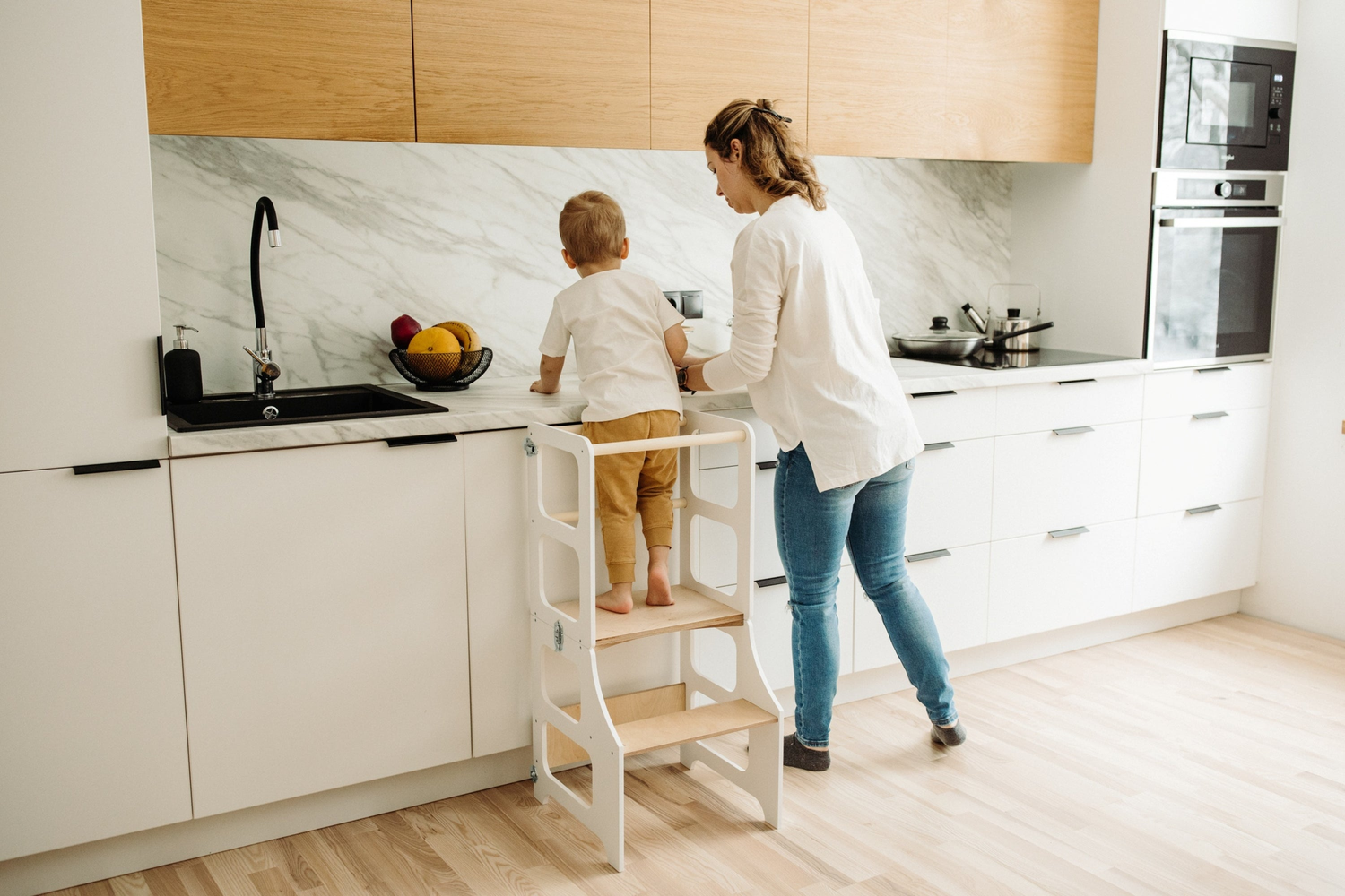 Auf dem Bild ist ein Montessori Lernturm mit Tafel sowie ein Mädchen welches den Lernturm gerade umklappt zu sehen.