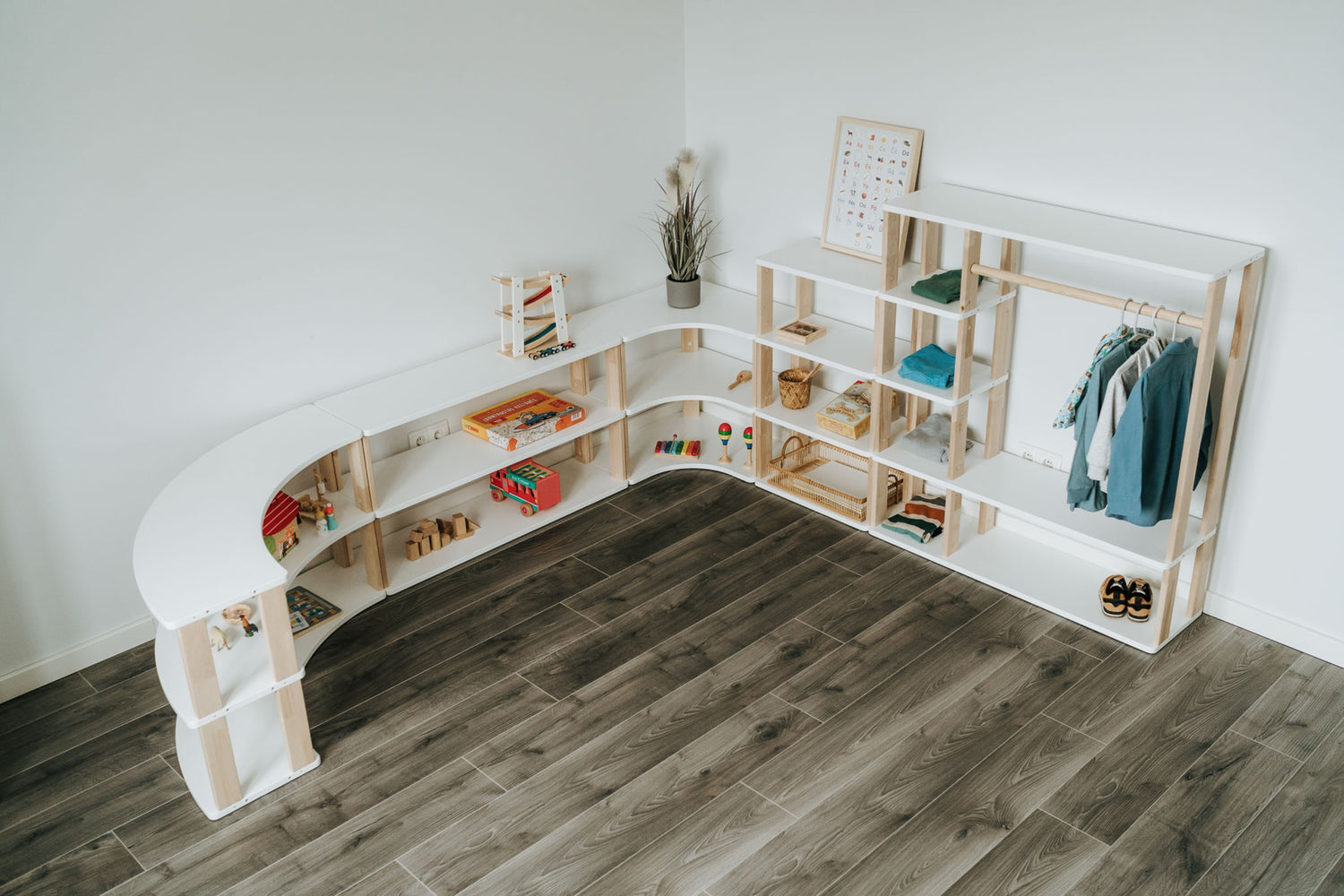 Verschiedene Montessori Möbel der MODURA Kollektion zusammengestellt. Darunter Montessori Kinderregale in verschiedenen Formen und ein Montessori Kleiderschrank.